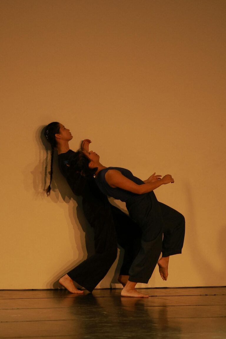 Two dancers perform a contemporary routine against a minimalist backdrop.